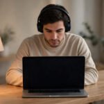 Person wearing headphones in deep focus at a minimalist desk with phone face-down and out of reach, for how to improve concentration.